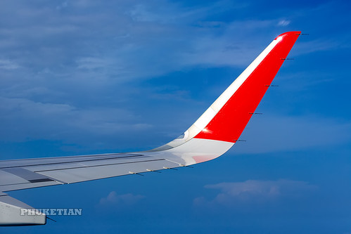 Wing of the plane AirAsia with red winglets in flight in blue sky    XOKA0058bs ©  Phuket@photographer.net