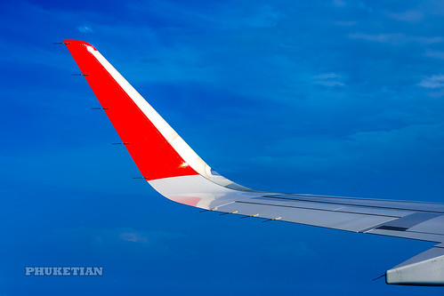 Wing of the plane AirAsia with red winglets in flight in blue sky     XOKA0058b2s ©  Phuket@photographer.net