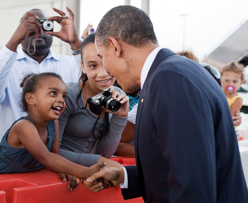: President Barack Obama shakes hands with a young girl.