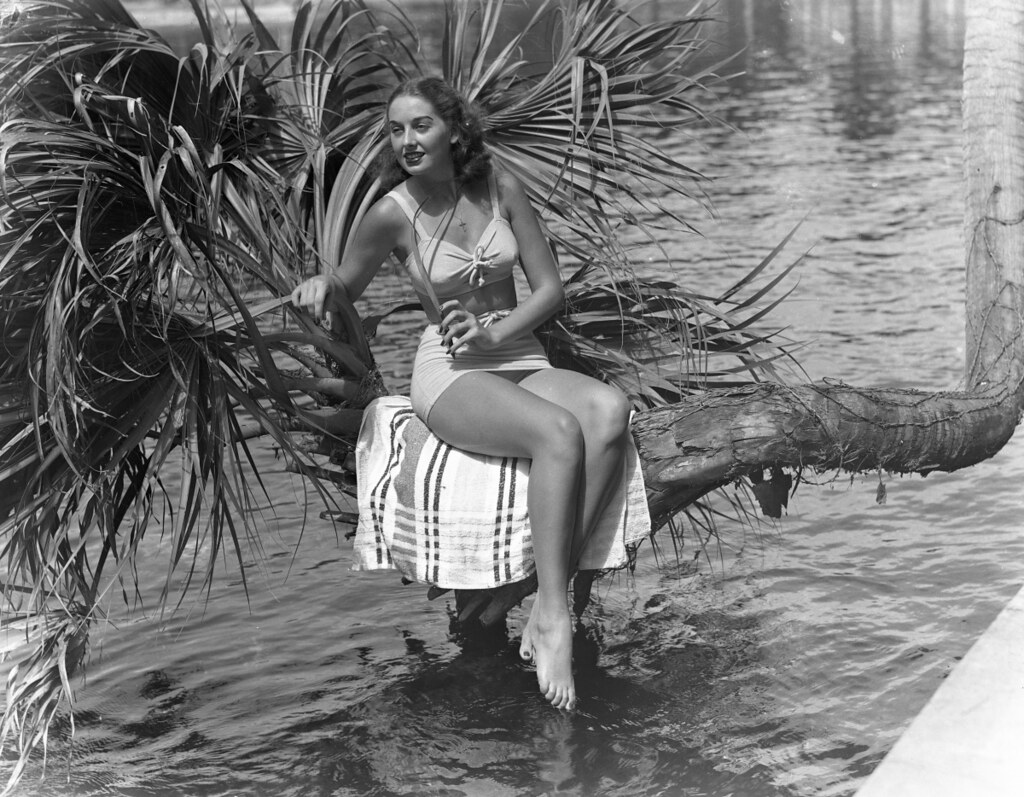 : Jackie Bingham in a Jantzen bathing suit posing on the lucky horseshoe palm tree at Silver Springs