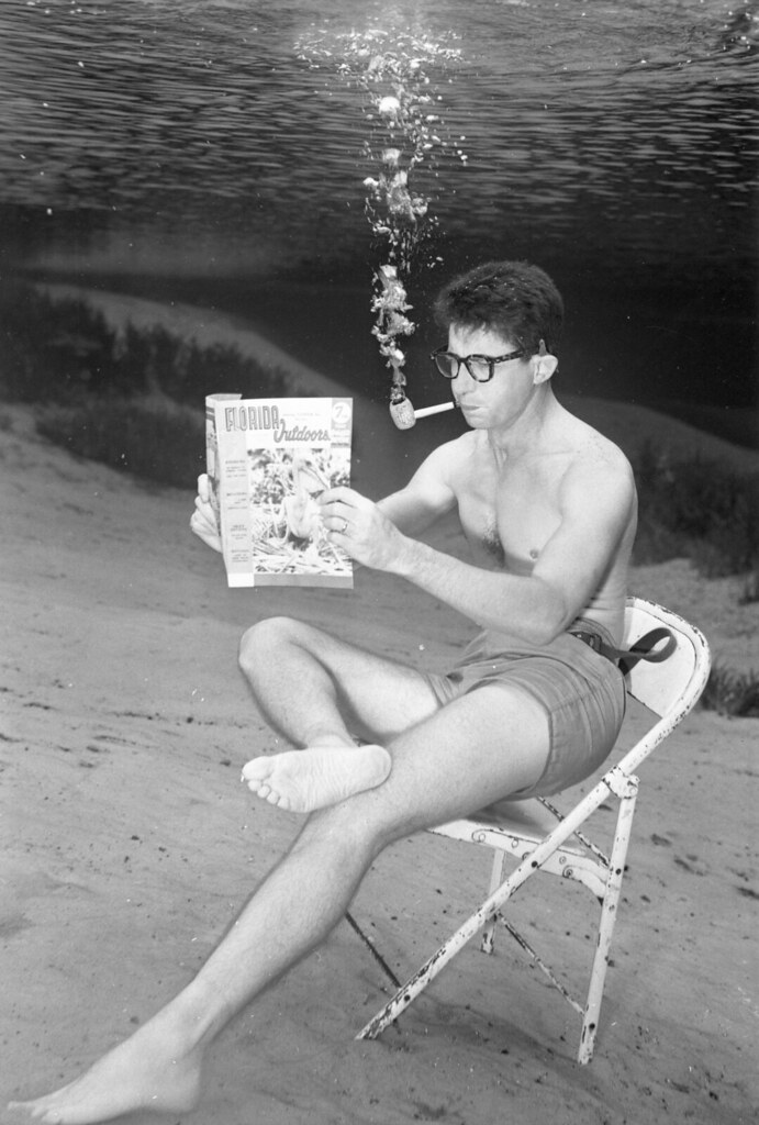 : Man reading the November 1956 Florida Outdoors magazine underwater at Silver Springs