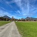 Road between two fields with Wildbarren (left) and Kranzhorn mountain near Oberaudorf in the river Inn valley in Bavaria, Germany