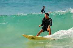 Surfing in the cool waves at Nai Harn Beach, Phuket, Thailand.