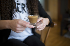 Close-up of a cup of creamy coffee in a young woman's hands