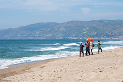Malibu, California - March 26, 2019: Adult tourists take selfies and photos, posing with umbrella props while enjoying the sunshine at Point Dume beach