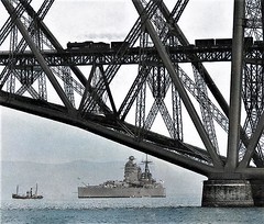 HMS Rodney approaching the Forth Bridge with steam train on the bridge