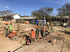 Seabees assigned to U.S. Naval Mobile Construction Battalion (NMCB) 3 Detail Timor-Leste and Forsa Defesa Timor-Leste service members work to backfill and compact footers using an auto level and a compaction sled for the construction of the Vila Nova thre