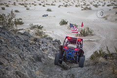 An off road vehicle descends down a hill in the desert.