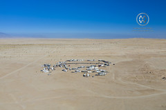 A group of campers line up their motorhomes in a circle in the desert.