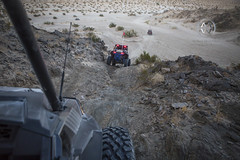 An off road vehicle descends down a hill in the desert.
