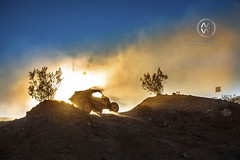 An off road vehicle climbs up a hill in the desert.