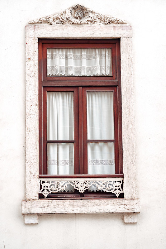 Ornate window with white moulding and lace curtains, typical of the architecture of Lisbon, Portugal<br/>© <a href="https://flickr.com/people/39908901@N06" target="_blank" rel="nofollow">39908901@N06</a> (<a href="https://flickr.com/photo.gne?id=50646904531" target="_blank" rel="nofollow">Flickr</a>)