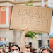 Öko-Demonstrantin hält Schild mit Text "Lobau bleibt!"