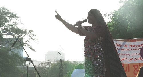Woman dressed in cultural outfit addressing the participants of a women's rights protest.