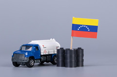 Oil truck and oil barrels with flag of Venezuela on grey background
