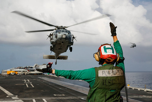 Aviation Structural Mechanic Airman Sydney Buckels directs an MH-60S Sea Hawk helicopter aboard USS Abraham Lincoln (CVN 72) in the South China Sea.