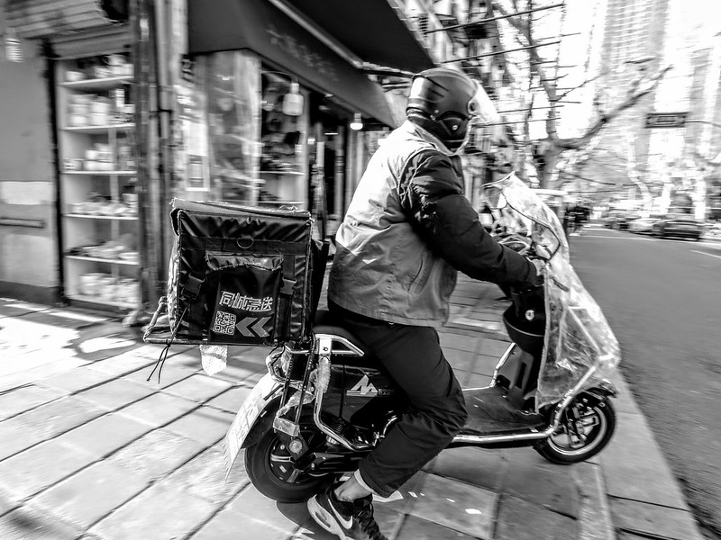 A delivery man driving into the street after taking an order on March 23, 2022, when many areas of Shanghai had already turned to lockdown. The bankruptcy of China's epidemic prevention strategy.<br/>© <a href="https://flickr.com/people/193575245@N03" target="_blank" rel="nofollow">193575245@N03</a> (<a href="https://flickr.com/photo.gne?id=52047000401" target="_blank" rel="nofollow">Flickr</a>)