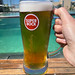 Mann hält im Urlaub Super Bock Bier im Bierglas in der Hand, mit Pool im Hintergrund