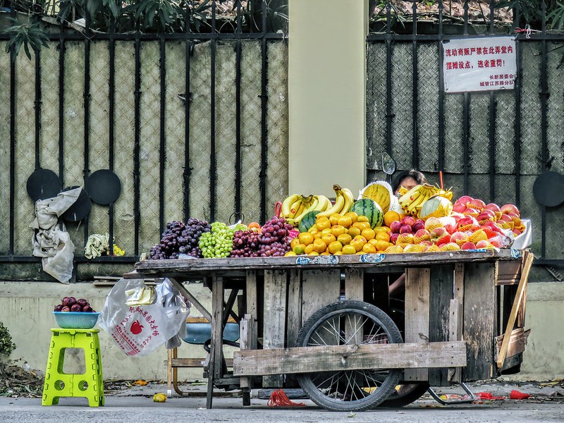 A beautiful fruit stall deep in the lane, despite a prominent 'no stall' warning on the wall behind the stallholder.<br/>© <a href="https://flickr.com/people/193575245@N03" target="_blank" rel="nofollow">193575245@N03</a> (<a href="https://flickr.com/photo.gne?id=52396928410" target="_blank" rel="nofollow">Flickr</a>)