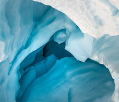 Illuminated by sunlight, the white and blue layers of an iceberg glow.