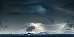Dramatic light dapples an island in the distance on the Antarctic Peninsula.