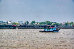 Tug boat with barges on the Chao Phraya river in Bangkok, Thailand
