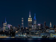 The Empire State Building, SUMMIT One Vanderbilt and the Chrysler Building light up the night sky and the Hudson River in Manhattan