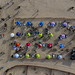 Aerial view of vacation tourists on sandy beach in marked out area with sunbeds and umbrellas in Lisbon, Portugal