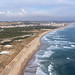Drohnenbild zeigt touristischen Sandstrand und Küste von Lissabon und Atlantischen Ozean