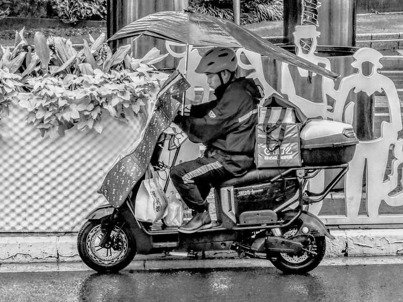 A delivery man in the rain, checking orders on his smartphone on a busy streetside<br/>© <a href="https://flickr.com/people/193575245@N03" target="_blank" rel="nofollow">193575245@N03</a> (<a href="https://flickr.com/photo.gne?id=53152060879" target="_blank" rel="nofollow">Flickr</a>)