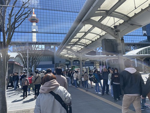写り込む京都タワーとバスを待つ長蛇の列