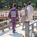 Three women in kimono walk across a wooden bridge in the Kenrokuen Garden, Kanazawa