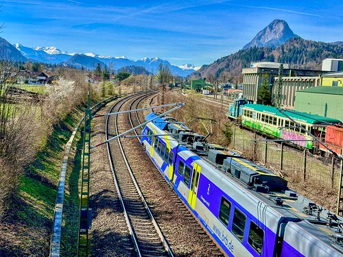 Regional express train passing the rail yard and the old cement mill in Kiefersfelden with Pendling mountain in the background in Bavaria, Germany