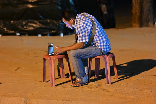 DSC_1559: a man sitting on a stool in the sand