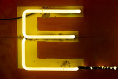 Neon yellow E letter illuminated on a sign at night