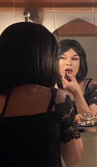 a young woman applying makeup in front of a mirror