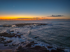 Dawn over the sea and rocks with clear skies