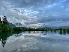 Lake Kreutsee with reflections of a clouded sky with Wildbarren (left) and Kranzhorn mountain flanking the river Inn valley near Kiefersfelden  in Bavaria, Germany