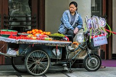 Woman selling fruits and fans in front of a theatre.