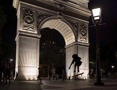 Silhouette of skateboarder jumping against the Washington Square Arch at night in Washington Square Park, Greenwich Village