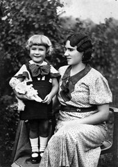 Vintage portrait of mother and daughter in 1930s Hungary holding a doll, outdoor setting.