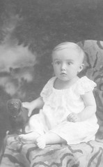 1925 portrait of a baby in Budapest, Hungary with toy dog, vintage studio setting.