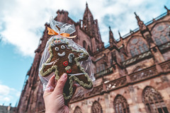 Hand holds a homemade gingerbread cookie for sale at a Christmas market in Strasbourg France, Notre Dame cathedral in background