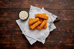 Pile of golden fried fish fingers with white garlic sauce